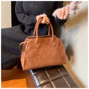 Dettaglio della borsa retrò in pelle scamosciata marrone portata da una modella in maglia