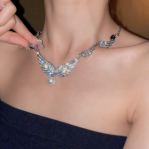 Close-up of sparkling winged earrings with silver needles and elegant pearl pendants