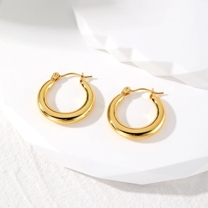 Minimalist polished gold geometric hoop earrings set on a white stone background
