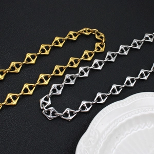 Macro view of gold and silver geometric diamond-shaped linked chains on black background