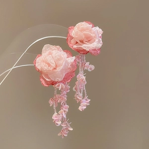 Macro detail of handmade pink flower earrings with delicate beaded tassel fringes