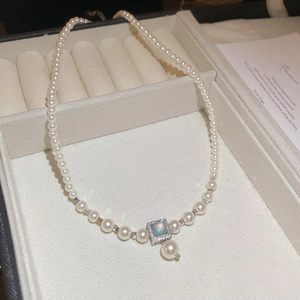 Close-up of a French pearl necklace with light blue square gemstone pendant in jewelry box