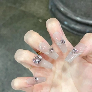 Close-up of translucent grey press-on nails with white lines and crystal bow decorations