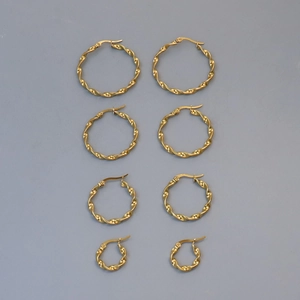 Flat lay of four different sizes of gold twisted hoop earrings on a blue background