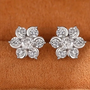 Sparkling zircon flower stud earrings in silver finish on orange velvet backdrop
