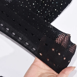 Vue macro du tissu en maille noire avec strass colorés montrant élasticité et texture