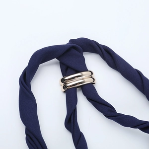 Close-up of the elegant twist knot detail and golden metal ring on dark blue fabric