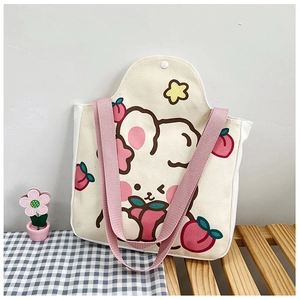 Close-up of canvas tote bag featuring cute cartoon rabbit and peach prints with pink straps