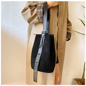 Detail of black matte suede bucket bag with adjustable leather shoulder strap
