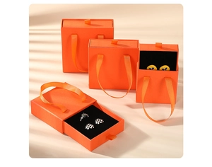 Detailed view of orange drawer jewelry boxes with satin handles and black velvet lining