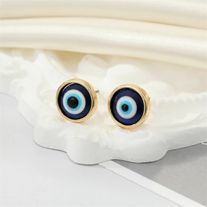 Detailed close-up of blue resin Evil Eye stud earrings with gold plating on white silk