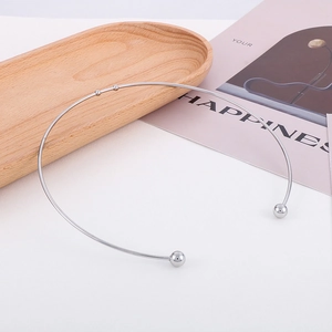 Détail du collier ras du cou en acier inoxydable argenté avec boules sur plateau bois