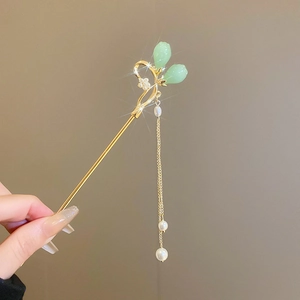 Détail du pic à cheveux doré avec boutons floraux verts et glands de perles élégants