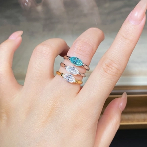 Close-up of three marquise cut rings in silver and gold with blue and white stones