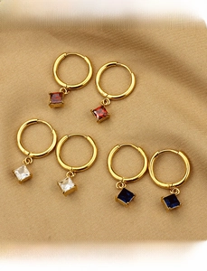 Detailed shot of three pairs of titanium steel earrings with red, white, and blue square zircons