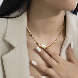 Detail of 18K gold-plated snake chain necklace featuring green rectangular zircons