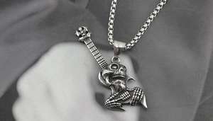 Close-up of silver titanium steel guitar pendant with skull and skeleton hand motifs