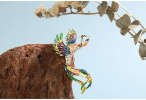 Detail of golden phoenix brooch with multi-color enamel wings and white rhinestones