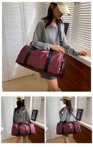 Detail view of burgundy fitness bag with wide black shoulder straps and side zipper pocket