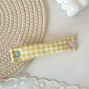 Detail of fabric cable organizer with heart-shaped buttons on a rustic woven mat