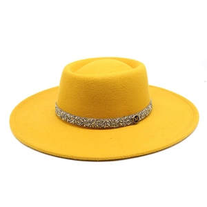 Detail of yellow wool fedora featuring rhinestone band and metallic M logo emblem