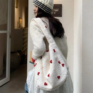 Detailed close-up of white plush tote bag with red heart embroidery and soft texture