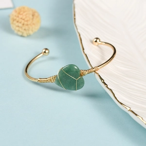 Luxurious gold heart bracelet featuring a green gemstone with wire wrap detail