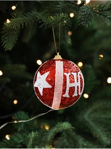 Detail of red glitter Christmas ball with white stars and HO lettering on a festive tree