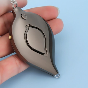 Macro shot of a gunmetal leaf-shaped personal alarm with keychain on blue background