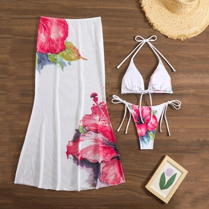 Flat lay of floral bikini set with matching mesh skirt on a wooden background