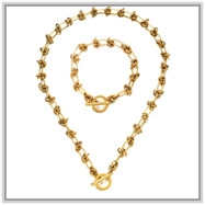 Detailed close-up of golden stainless steel necklace and bracelet set with T-bar closures