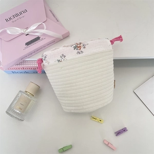 Detailed macro of a quilted drawstring pouch with floral trim and pink cotton cord