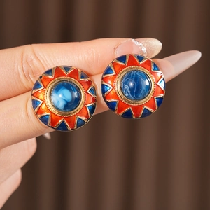 Close-up of vintage round earrings with blue orange enamel and gold-tone beaded edges
