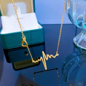 Macro view of golden heartbeat necklace with hollow heart pendant on reflective surface
