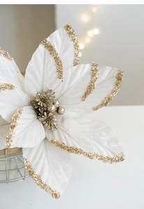 Close-up of white velvet Christmas flower with gold glitter edges and festive berry center