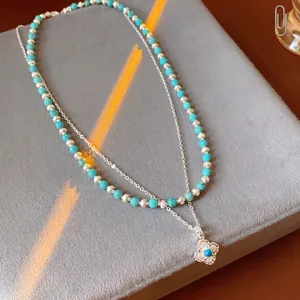 Double-layered turquoise beaded necklace with silver clover pendant and zircon accents