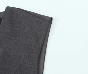 Detail of dark gray tailored vest showing fine stitching and woven fabric texture