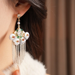 Detail of vintage fan-shaped earrings with pearls and long metal fringe on model