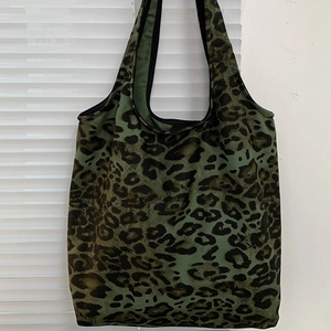 Borsa tote in tela con stampa leopardata verde con spallacci su parete bianca