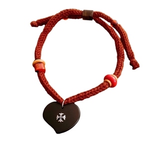 Handcrafted cord necklace with black heart pendant and silver floral motif on white background