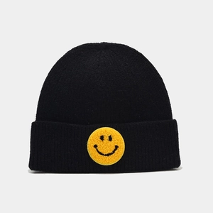 Gros plan de l'écusson sourire en chenille jaune sur le revers du bonnet noir