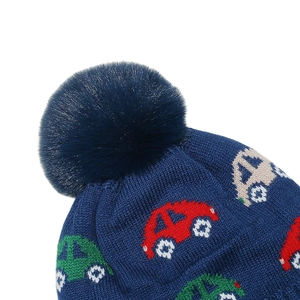 Detailed view of the dark blue knit hat with colorful car patterns and large faux fur pompom