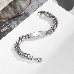Macro detail of silver stainless steel Cuban chain bracelet with smooth engravable curved bar