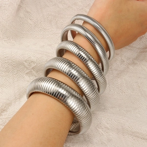 Detail view of five-piece stacked silver elastic snake bone bracelets on a female wrist
