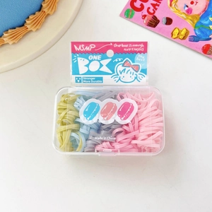Dettaglio di elastici per capelli colorati in scatola trasparente su marmo bianco