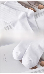 Detailed macro view of white cotton mid-calf socks with seamless toe and ribbed cuffs