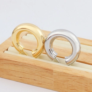 Détail des créoles cylindriques de 28mm en finitions or et argent sur support en bois