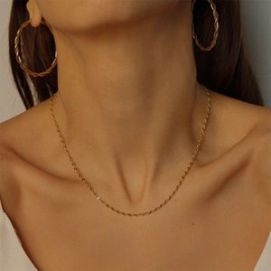 Detail of golden twist rope chain necklace and matching earrings on a female model