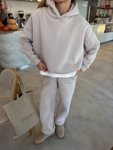 Detail van havermoutkleurige hoodie en joggingbroek in een gezellige café-omgeving