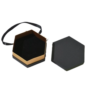 Elegant hexagonal jewelry gift box with black and gold textured finish and ribbon handle